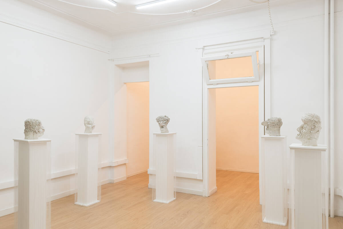Installation view of Calipso by Cleo Fariselli at Clima Gallery, Milano: white sculpted heads on white pedestals in a white room